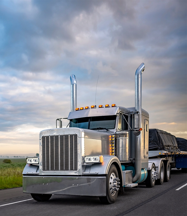 Chrome semi truck with dual exhaust stacks hauling cargo on highway