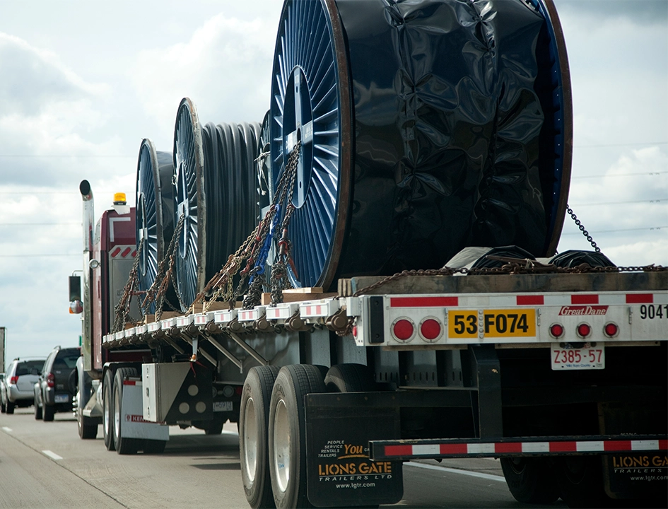 Heavy haul truck carrying large industrial cable reels on highway