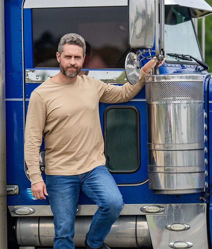 Truck driver posing next to blue semi truck with chrome accessories